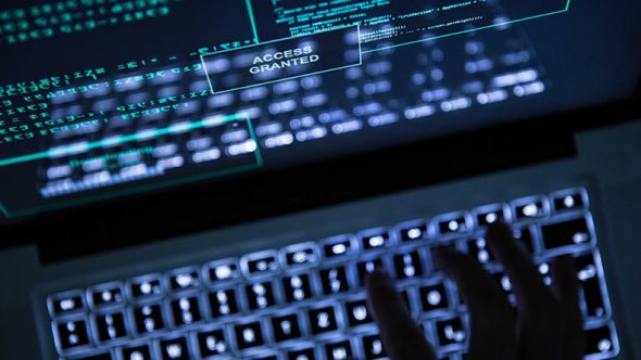 A hand reaching for a laptop keyboard displaying 'ACCESS GRANTED' on the screen.