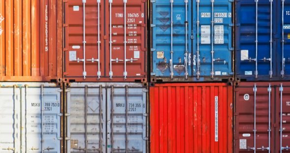 A stacked arrangement of various shipping containers in different colors,including red,blue,orange,and gray.